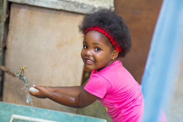 niña afrodescendiente lavándose las manos